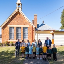 Her Excellency with a group of school children and teachers standing in front of a school building